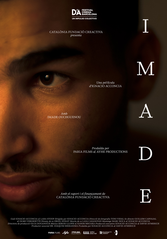 Cartell de la pel·lícula IMADE. Primer pla en ombres del rostre d’un home jove, amb la mirada intensa i misteriosa dirigida a la càmera. Sobre el fons fosc hi apareixen els crèdits de la pel·lícula.