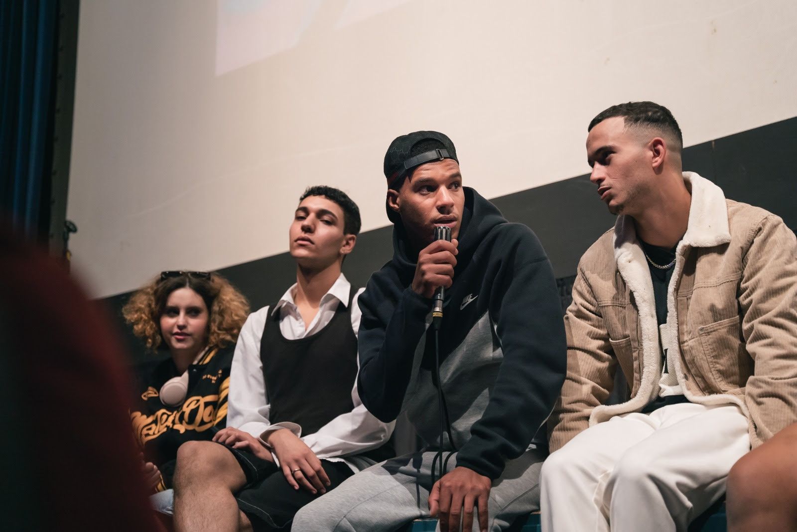 Joves migrats parlen asseguts a l'escenari del teatre comtal de Ripoll amb joves del Ripollès 