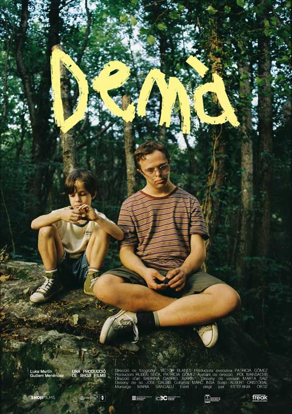 Pòster de la pel·lícula 'Demà'. Mostra dos nois, un amb síndrome de Down, que estan asseguts sobre una roca enmig d'un bosc. El títol, 'Demà', està escrit amb lletres grogues a la part superior de la imatge i el nom dels actors, Luka Martín i Guillem Menéndez, es troben a la part inferior esquerra.